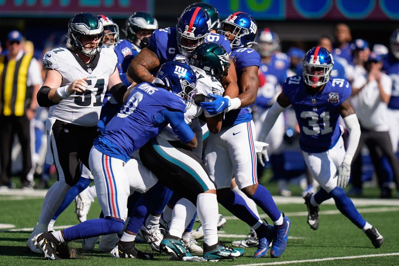 New York Giants defensive tackle Dexter Lawrence II (97) and linebacker Brian Burns (0) stop Philadelphia Eagles running back Saquon Barkley (26) during the first quarter of an NFL football game, Sunday, Oct. 20, 2024, in East Rutherford, N.J. (AP Photo/Frank Franklin II)