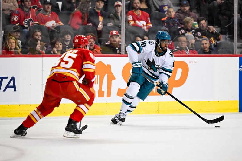 Feb 15, 2024; Calgary, Alberta, CAN; San Jose Sharks left wing Anthony Duclair (10) skates with the puck against Calgary Flames defenseman Noah Hanifin (55) during the first period at Scotiabank Saddledome. Mandatory Credit: Brett Holmes-USA TODAY Sports