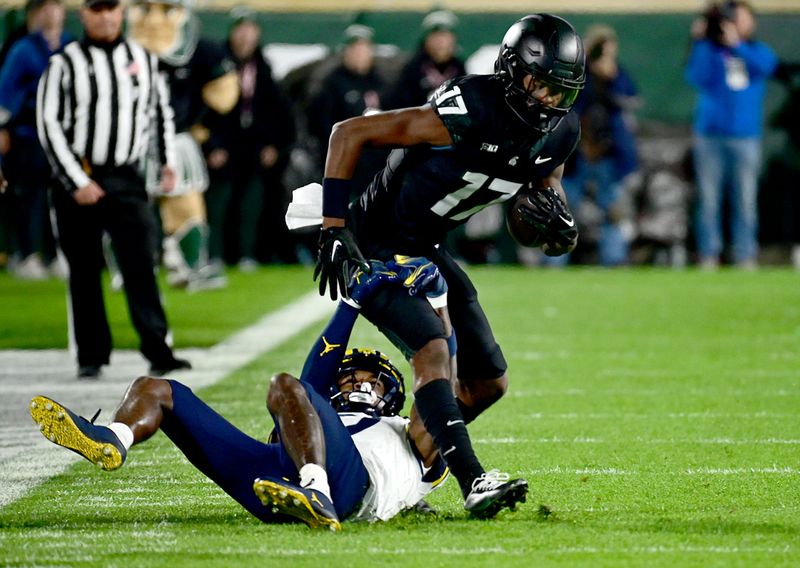 Oct 21, 2023; East Lansing, Michigan, USA;  Michigan State Spartans wide receiver Tre Mosley (17) pulls down a pass and Michigan Wolverines defensive back Makari Paige (7) pulls him down in the first quarter at Spartan Stadium. Mandatory Credit: Dale Young-USA TODAY Sports