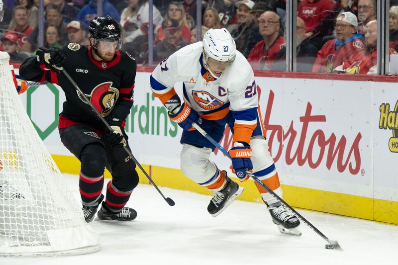 Nov 7, 2024; Ottawa, Ontario, CAN; New York Islanders left wing Anders Lee (27) moves the puck away from Ottawa Senators defenseman Jake Sanderson (85) in the second period at the Canadian Tire Centre. Mandatory Credit: Marc DesRosiers-Imagn Images