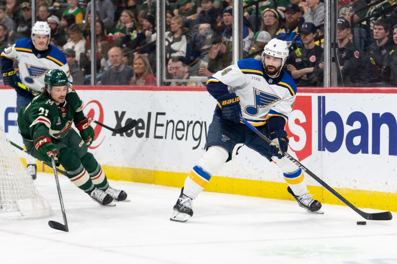 Apr 8, 2023; Saint Paul, Minnesota, USA; St. Louis Blues defenseman Nick Leddy (4) skates behind the net Minnesota Wild right wing Brandon Duhaime (21) defends in the third period at Xcel Energy Center. Mandatory Credit: Matt Blewett-USA TODAY Sports