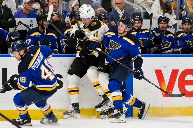 Nov 12, 2024; St. Louis, Missouri, USA;  St. Louis Blues center Alexandre Texier (9) checks Boston Bruins center Trent Frederic (11) during the first period at Enterprise Center. Mandatory Credit: Jeff Curry-Imagn Images