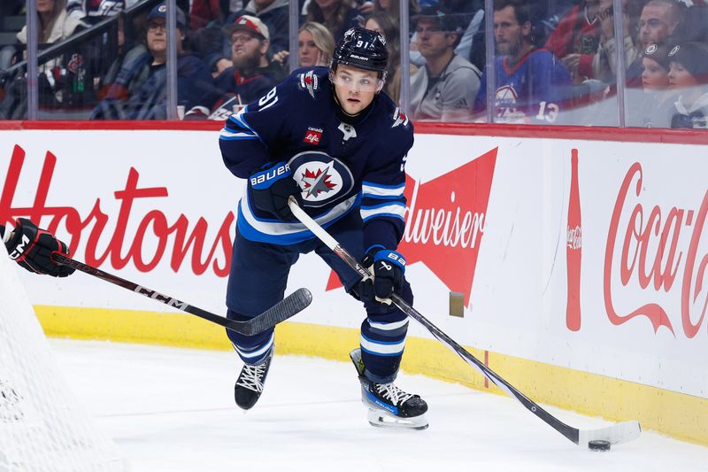 Oct 11, 2024; Winnipeg, Manitoba, CAN; Winnipeg Jets forward Cole Perfetti (91) looks to make a pass behind the Chicago Blackhawks net during the second period at Canada Life Centre. Mandatory Credit: Terrence Lee-Imagn Images