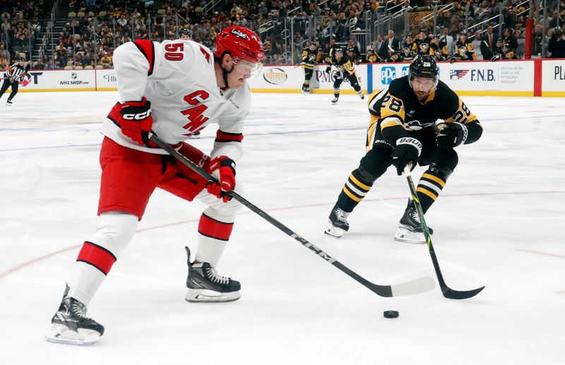 Oct 18, 2024; Pittsburgh, Pennsylvania, USA;  Carolina Hurricanes left wing Eric Robinson (50) skates with the puck against Pittsburgh Penguins defenseman Marcus Pettersson (28) during the second period at PPG Paints Arena. Mandatory Credit: Charles LeClaire-Imagn Images