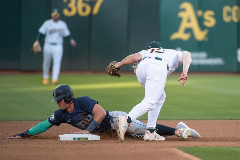 Jun 4, 2024; Oakland, California, USA; Seattle Mariners shortstop Dylan Moore (25) steals second base against the Oakland Athletics shortstop Max Schuemann (12) during the fourth inning at Oakland-Alameda County Coliseum. Mandatory Credit: Ed Szczepanski-USA TODAY Sports