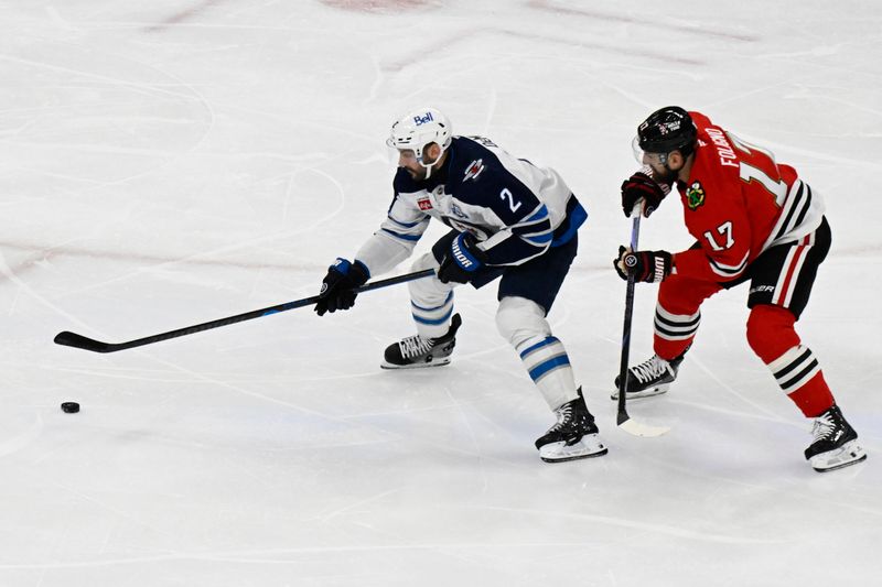 Jan 19, 2026; Chicago, Illinois, USA;  Winnipeg Jets defenseman Dylan DeMelo (2) plays the puck against Chicago Blackhawks left wing Nick Foligno (17) during the first period at United Center. Mandatory Credit: Matt Marton-Imagn Images