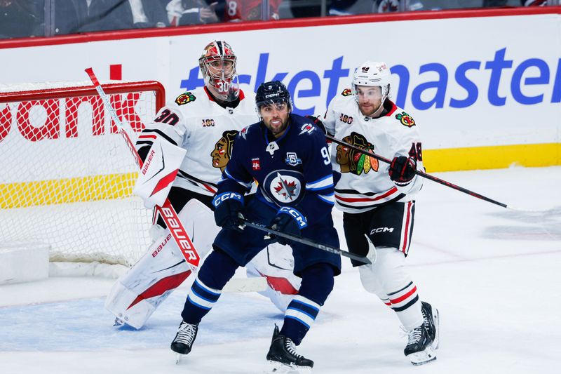 Oct 30, 2025; Winnipeg, Manitoba, CAN;  Winnipeg Jets forward Alex Iafallo (9) jostles for position with Chicago Blackhawks defenseman Matt Grzelcyk (48) in front of Chicago Blackhawks goalie Spencer Knight (30) during the third period at Canada Life Centre. Mandatory Credit: Terrence Lee-Imagn Images
