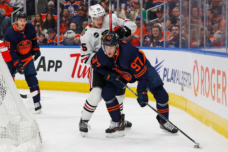 Jan 25, 2024; Edmonton, Alberta, CAN; Chicago Blackhawks defensemen Kevin Korchinski (55) and Edmonton Oilers forward Connor McDavid (97) battle for a loose puck during the first period at Rogers Place. Mandatory Credit: Perry Nelson-USA TODAY Sports