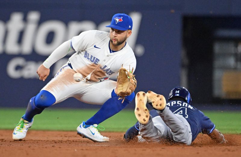 May 14, 2025; Toronto, Ontario, CAN;  Toronto Blue Jays shortstop Bo Bichette (11) takes the throw from the plate before tagging out Tampa Bay Rays left fielder Chandler Simpson (14) who was trying to steal second base in the third inning at Rogers Centre. Mandatory Credit: Dan Hamilton-Imagn Images