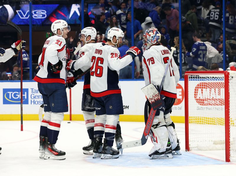 Nov 27, 2024; Tampa, Florida, USA; Washington Capitals goaltender Charlie Lindgren (79), center Nic Dowd (26), right wing Tom Wilson (43) and center Aliaksei Protas (21) celebrate after they beat the Tampa Bay Lightning at Amalie Arena. Mandatory Credit: Kim Klement Neitzel-Imagn Images