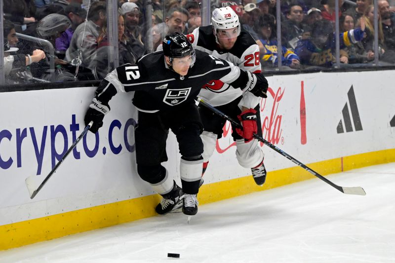 Mar 3, 2024; Los Angeles, California, USA; Los Angeles Kings left wing Trevor Moore (12) and New Jersey Devils right wing Timo Meier (28) battle along the boards in the second period at Crypto.com Arena. Mandatory Credit: Jayne Kamin-Oncea-USA TODAY Sports