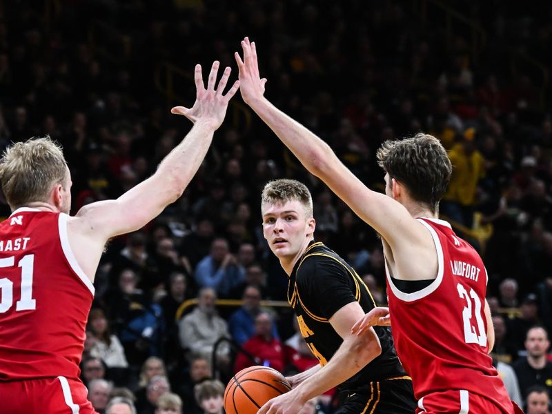 Feb 17, 2026; Iowa City, Iowa, USA; Iowa Hawkeyes guard Bennett Stirtz (14) is defended by Nebraska Cornhuskers forward Pryce Sandfort (21) and forward Rienk Mast (51) during the second half at Carver-Hawkeye Arena. Mandatory Credit: Jeffrey Becker-Imagn Images