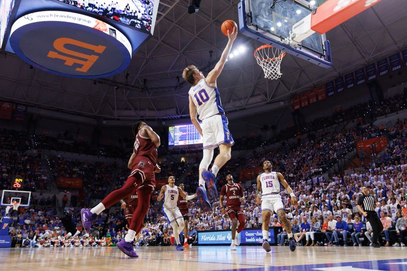 Feb 15, 2025; Gainesville, Florida, USA; Florida Gators forward Thomas Haugh (10) makes a layup over South Carolina Gamecocks forward Collin Murray-Boyles (30) during the second half at Exactech Arena at the Stephen C. O'Connell Center. Mandatory Credit: Matt Pendleton-Imagn Images