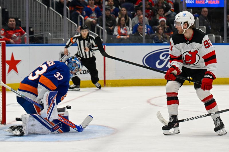 Dec 23, 2025; Elmont, New York, USA;  New York Islanders goaltender David Rittich (33) makes a save on New Jersey Devils center Dawson Mercer (91) during the third period at UBS Arena. Mandatory Credit: Dennis Schneidler-Imagn Images