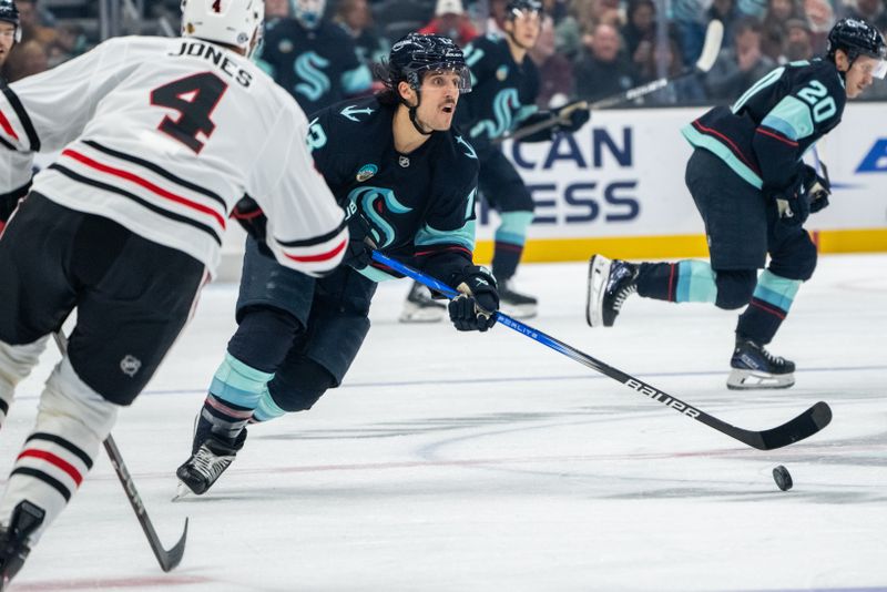 Nov 14, 2024; Seattle, Washington, USA;  Seattle Kraken forward Brandon Tanev (13) skates against Chicago Blackhawks defenseman Seth Jones (4) during the first period at Climate Pledge Arena. Mandatory Credit: Stephen Brashear-Imagn Images