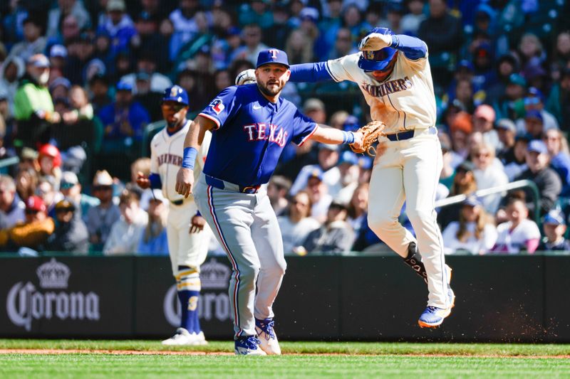 Apr 13, 2025; Seattle, Washington, USA; Seattle Mariners designated hitter Jorge Polanco (7) evades a tag by Texas Rangers first baseman Jake Burger (21) during the sixth inning at T-Mobile Park. Burger was given an error on the play. Mandatory Credit: Joe Nicholson-Imagn Images