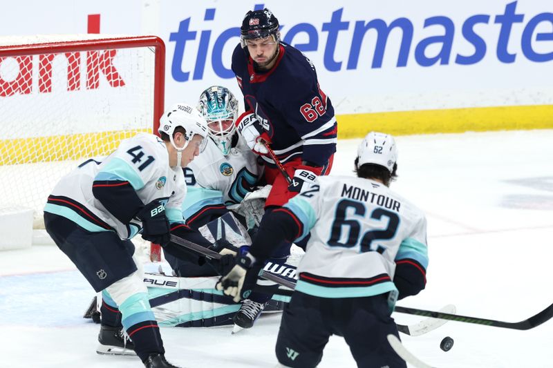 Jan 16, 2025; Winnipeg, Manitoba, CAN; Seattle Kraken goaltender Joey Daccord (35) and Winnipeg Jets right wing Nino Niederreiter (62) eye an incoming shot in the third period at Canada Life Centre. Mandatory Credit: James Carey Lauder-Imagn Images