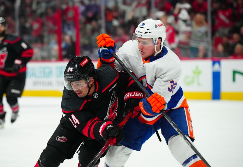 Apr 22, 2024; Raleigh, North Carolina, USA; Carolina Hurricanes center Seth Jarvis (24) and New York Islanders center Kyle MacLean (32) battle for position during the third period in game two of the first round of the 2024 Stanley Cup Playoffs at PNC Arena. Mandatory Credit: James Guillory-USA TODAY Sports