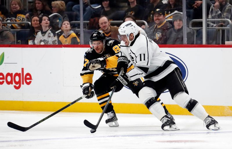 Feb 18, 2024; Pittsburgh, Pennsylvania, USA;  Los Angeles Kings center Anze Kopitar (11) moves the puck against Pittsburgh Penguins center Sidney Crosby (87) during the first period at PPG Paints Arena. Mandatory Credit: Charles LeClaire-USA TODAY Sports