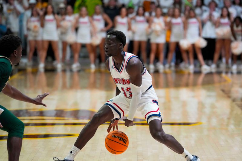 Jan 27, 2024; Laramie, Wyoming, USA; Wyoming Cowboys guard Akuel Kot (13) dribbles against Colorado State Rams forward Isaiah Stevens (4) during overtime at Arena-Auditorium. Mandatory Credit: Troy Babbitt-USA TODAY Sports