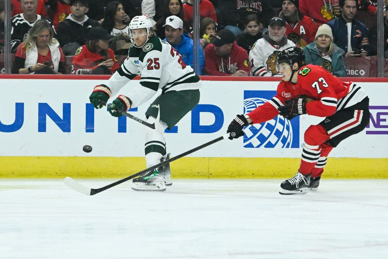 Nov 10, 2024; Chicago, Illinois, USA;  Minnesota Wild defenseman Jonas Brodin (25) flips the puck past Chicago Blackhawks left wing Lukas Reichel (73) during the first period at the United Center. Mandatory Credit: Matt Marton-Imagn Images