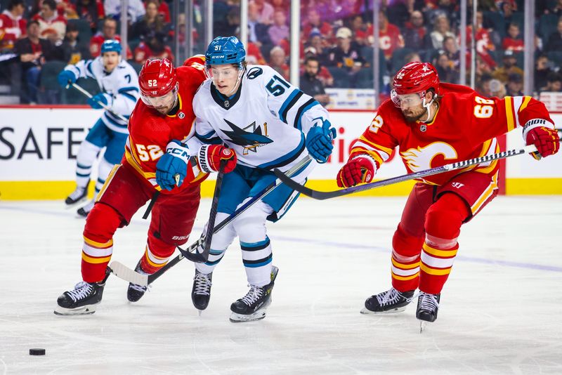 Apr 18, 2024; Calgary, Alberta, CAN; San Jose Sharks right wing Collin Graf (51) battles for the puck with Calgary Flames defenseman MacKenzie Weegar (52) and defenseman Daniil Miromanov (62) during the first period at Scotiabank Saddledome. Mandatory Credit: Sergei Belski-USA TODAY Sports