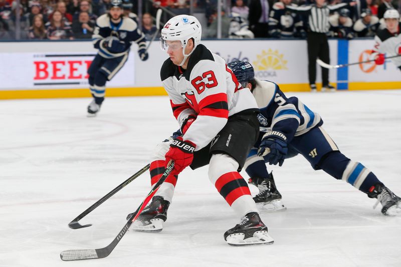Dec 31, 2025; Columbus, Ohio, USA; New Jersey Devils left wing Jesper Bratt (63) carries the puck as Columbus Blue Jackets defenseman Denton Mateychuk (5) defends during the third period at Nationwide Arena. Mandatory Credit: Russell LaBounty-Imagn Images