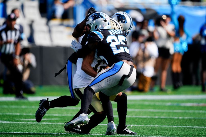 New Orleans Saints wide receiver Chris Olave gets hit by Carolina Panthers cornerback Michael Jackson and safety Xavier Woods during the first half of an NFL football game Sunday, Nov. 3, 2024, in Charlotte, N.C. Olave was taken off the field after getting hurt on the play. (AP Photo/Jacob Kupferman)