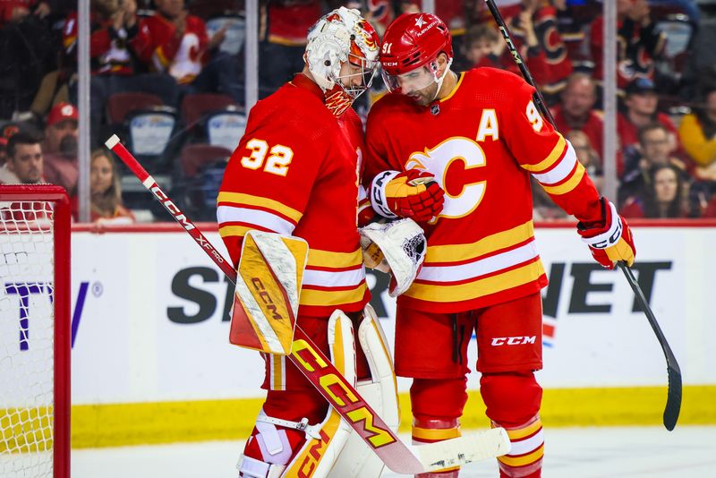 Apr 18, 2024; Calgary, Alberta, CAN; Calgary Flames goaltender Dustin Wolf (32) and center Nazem Kadri (91) celebrates win against San Jose Sharks at Scotiabank Saddledome. Mandatory Credit: Sergei Belski-USA TODAY Sports