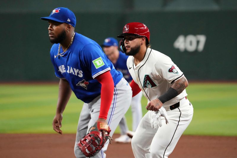 Jul 13, 2024; Phoenix, Arizona, USA; Arizona Diamondbacks catcher Jose Herrera (11) leads off first base as Toronto Blue Jays first base Vladimir Guerrero Jr. (27) covers during the third inning at Chase Field. Mandatory Credit: Joe Camporeale-USA TODAY Sports