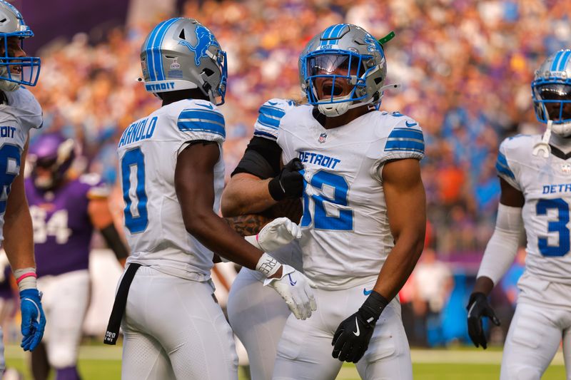 Detroit Lions safety Brian Branch (32) reacts to his interception with Terrion Arnold (0) during the first half of an NFL football game against the Minnesota Vikings Sunday, Oct. 20, 2024, in Minneapolis. (AP Photo/Bruce Kluckhohn)