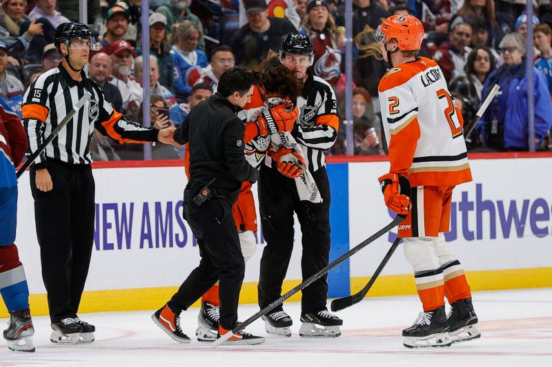 Nov 11, 2025; Denver, Colorado, USA; Anaheim Ducks left wing Alex Killorn (17) is helped off the ice by head athletic trainer Chad Walker and referee Chris Schlenker (3) as defenseman Jackson Lacombe (2) and referee Jean Hebert (15) look on in the third period against the Colorado Avalanche at Ball Arena. Mandatory Credit: Isaiah J. Downing-Imagn Images