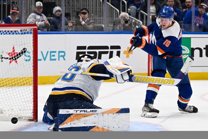 Mar 5, 2024; Elmont, New York, USA;  New York Islanders right wing Simon Holmstrom (10) attempts a shot that does not cross the goal line behind St. Louis Blues goaltender Joel Hofer (30) during the second period at UBS Arena. Mandatory Credit: Dennis Schneidler-USA TODAY Sports