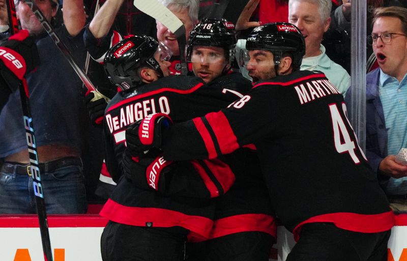 Apr 30, 2024; Raleigh, North Carolina, USA; Carolina Hurricanes center Jack Drury (18) is congratulated by left wing Jordan Martinook (48) and defenseman Tony DeAngelo (77) after his goal against the New York Islanders during the third period in game five of the first round of the 2024 Stanley Cup Playoffs at PNC Arena. Mandatory Credit: James Guillory-USA TODAY Sports