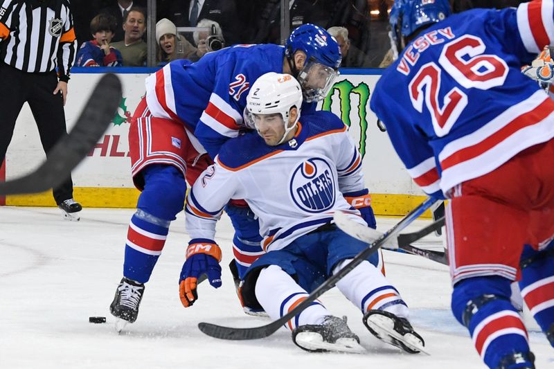 Dec 22, 2023; New York, New York, USA;  Edmonton Oilers defenseman Evan Bouchard (2) and New York Rangers center Barclay Goodrow (21) battle for a loose puck during the second period at Madison Square Garden. Mandatory Credit: Dennis Schneidler-USA TODAY Sports