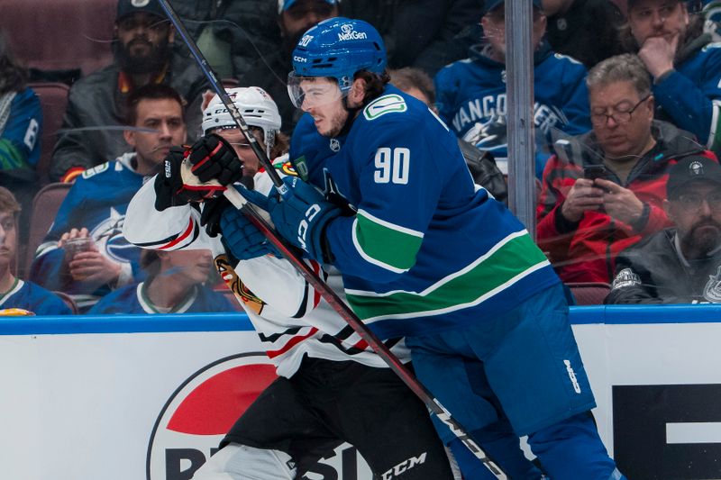 Mar 15, 2025; Vancouver, British Columbia, CAN; Vancouver Canucks defenseman Vittorio Mancini (90) checks Chicago Blackhawks forward Landon Slaggert (84) in the second period at Rogers Arena. Mandatory Credit: Bob Frid-Imagn Images
