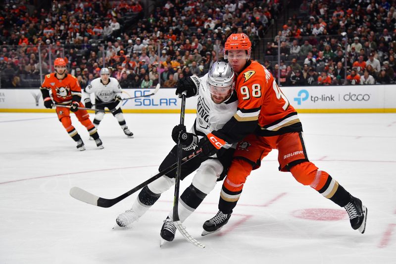 Nov 28, 2025; Anaheim, California, USA; Los Angeles Kings right wing Adrian Kempe (9) plays for the puck against Anaheim Ducks defenseman Pavel Mintyukov (98) during the third period at Honda Center. Mandatory Credit: Gary A. Vasquez-Imagn Images