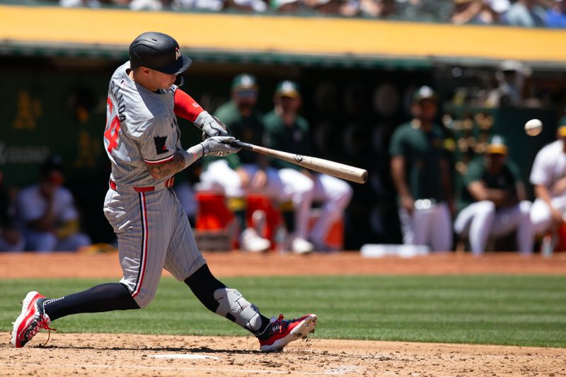 Jun 22, 2024; Oakland, California, USA; Minnesota Twins third baseman Jose Miranda (64) connects for an RBI double against the Oakland Athletics during the third inning at Oakland-Alameda County Coliseum. Mandatory Credit: D. Ross Cameron-USA TODAY Sports