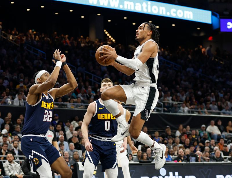 AUSTIN, TX - MARCH 15: Tre Jones #33 of the San Antonio Spurs goes to the basket over Jake Nnaji #22 of the Denver Nuggets in the first half at Moody Center on March 15, 2024 in Austin, Texas. NOTE TO USER: User expressly acknowledges and agrees that, by downloading and or using this photograph, User is consenting to terms and conditions of the Getty Images License Agreement. (Photo by Ronald Cortes/Getty Images)