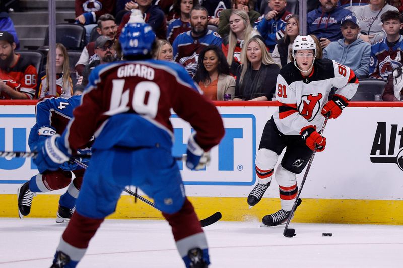 Nov 7, 2023; Denver, Colorado, USA; New Jersey Devils center Dawson Mercer (91) controls the puck as Colorado Avalanche defenseman Samuel Girard (49) looks on in the first period at Ball Arena. Mandatory Credit: Isaiah J. Downing-USA TODAY Sports