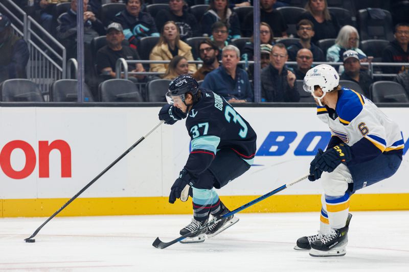 Oct 8, 2024; Seattle, Washington, USA; Seattle Kraken center Yanni Gourde (37) shields the puck from St. Louis Blues defenseman Philip Broberg (6) during the first period at Climate Pledge Arena. Mandatory Credit: Caean Couto-Imagn Images