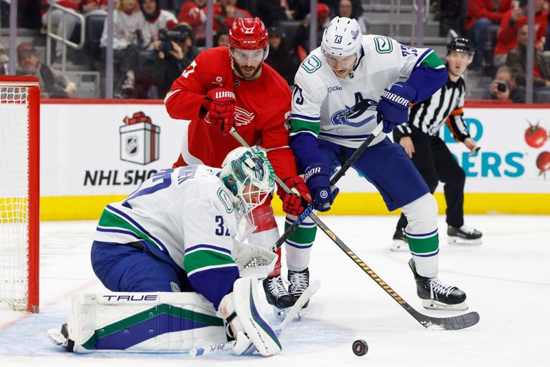 Dec 1, 2024; Detroit, Michigan, USA;  Vancouver Canucks goaltender Kevin Lankinen (32) makes a save in front of defenseman Vincent Desharnais (73) and Detroit Red Wings center Michael Rasmussen (27) in the second period at Little Caesars Arena. Mandatory Credit: Rick Osentoski-Imagn Images