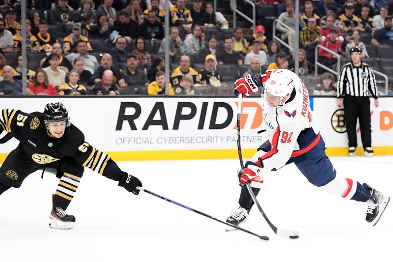 Oct 3, 2023; Boston, Massachusetts, USA; Washington Capitals center Evgeny Kuznetsov (92) shoots the puck while Boston Bruins center Matthew Poitras (51) defends during overtime at TD Garden. Mandatory Credit: Bob DeChiara-USA TODAY Sports