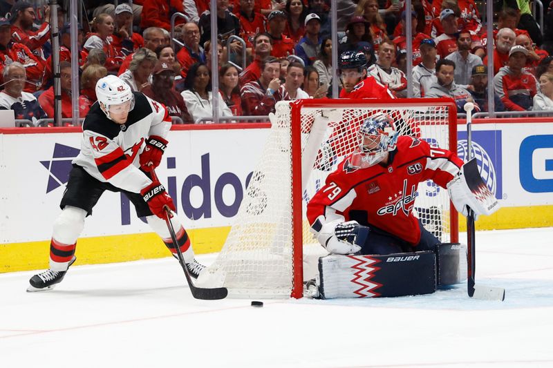 Oct 12, 2024; Washington, District of Columbia, USA; New Jersey Devils center Curtis Lazar (42) passes the puck in front of Washington Capitals goaltender Charlie Lindgren (79) in the second period at Capital One Arena. Mandatory Credit: Geoff Burke-Imagn Images