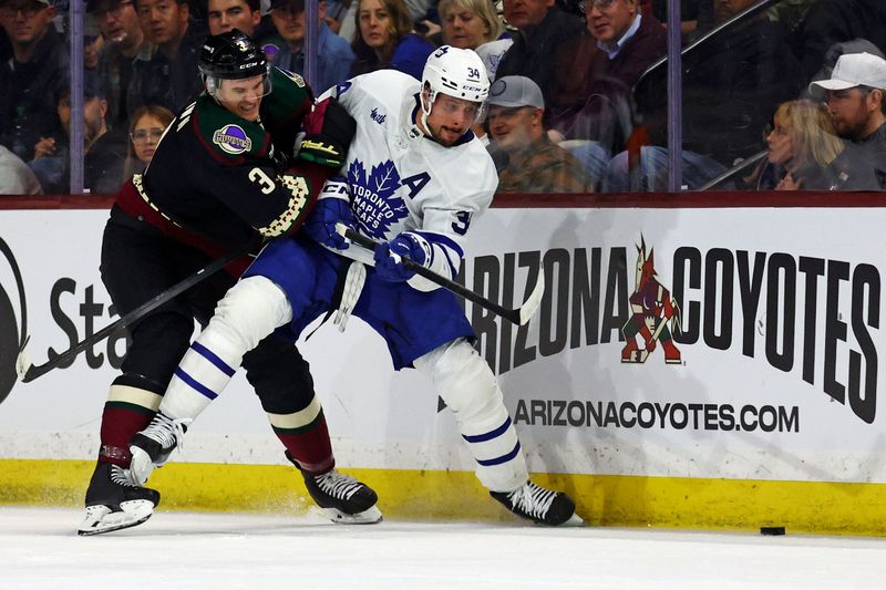 Feb 21, 2024; Tempe, Arizona, USA; Toronto Maple Leafs center Auston Matthews (34) and  Arizona Coyotes defenseman Josh Brown (3) go for the puck during the second period at Mullett Arena. Mandatory Credit: Mark J. Rebilas-USA TODAY Sports