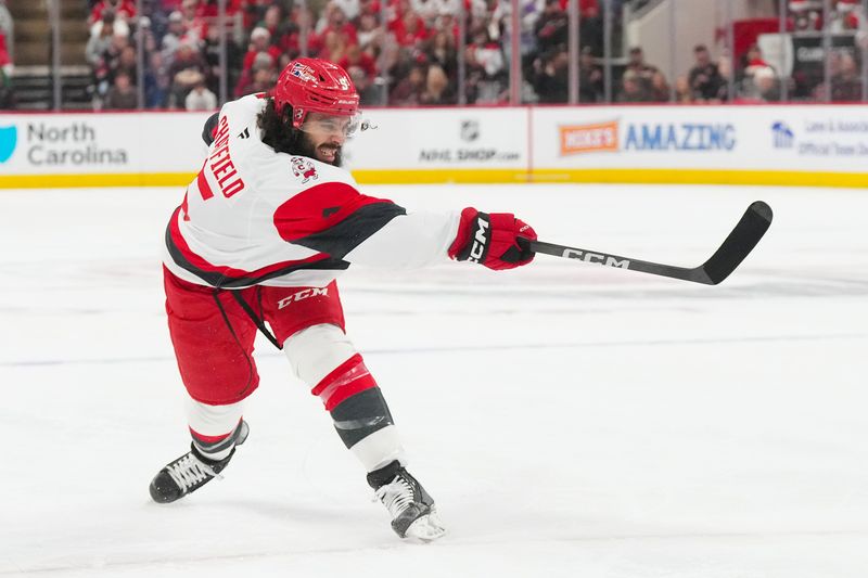 Dec 23, 2025; Raleigh, North Carolina, USA;  Carolina Hurricanes defenseman Jalen Chatfield (5) takes a shot against the Florida Panthers during the first period at Lenovo Center. Mandatory Credit: James Guillory-Imagn Images