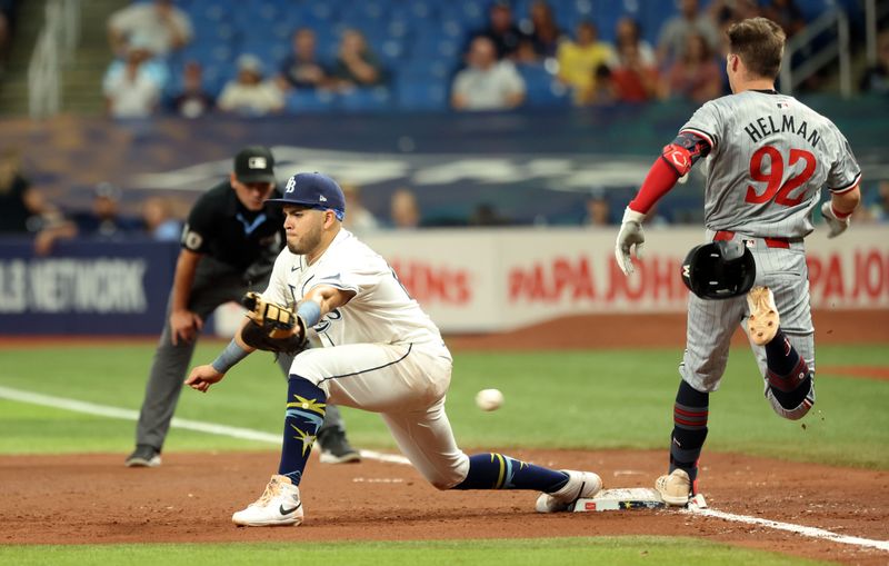 Sep 3, 2024; St. Petersburg, Florida, USA;  Minnesota Twins outfielder Michael Helman (92) is safe at first base for his first career hit as Tampa Bay Rays first base Jonathan Aranda (62) attempted to catch the ball during the fifth inning at Tropicana Field. Mandatory Credit: Kim Klement Neitzel-Imagn Images