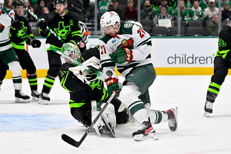 Jan 10, 2024; Dallas, Texas, USA; Minnesota Wild right wing Brandon Duhaime (21) is hit by a Wild slap shot as he attempts a shot on Dallas Stars goaltender Scott Wedgewood (41) during the first period at the American Airlines Center. Mandatory Credit: Jerome Miron-USA TODAY Sports