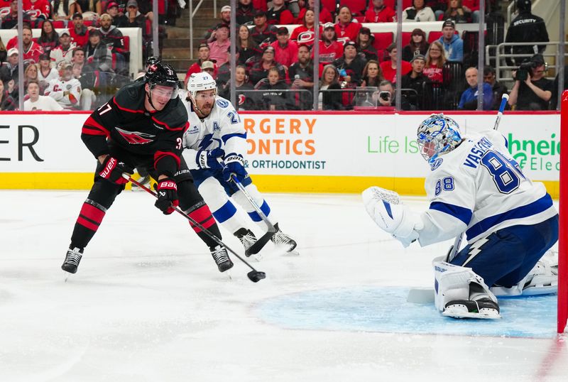 Oct 11, 2024; Raleigh, North Carolina, USA;  Carolina Hurricanes right wing Andrei Svechnikov (37) has a scoring attempt against Tampa Bay Lightning goaltender Andrei Vasilevskiy (88) and defenseman Ryan McDonagh (27) during the first period at PNC Arena. Mandatory Credit: James Guillory-Imagn Images