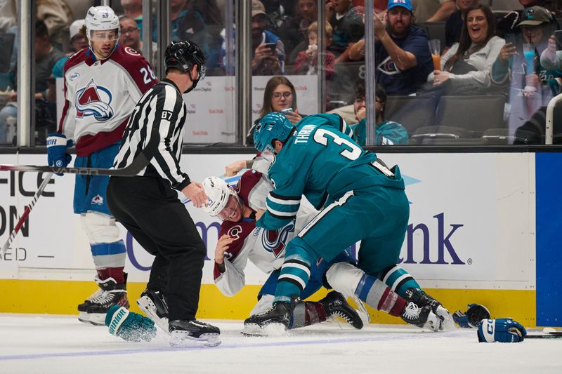 Oct 20, 2024; San Jose, California, USA; San Jose Sharks defenseman Henry Thrun (3) fights against Colorado Avalanche right wing Logan O'Connor (25) as left wing Miles Wood (28) and linesman Devin Berg (87) watch the play during the second period at SAP Center at San Jose. Mandatory Credit: Robert Edwards-Imagn Images